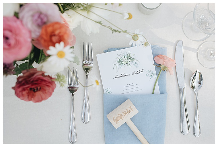 Dusty blue place settings with pastel pink florals and custom crab mallets