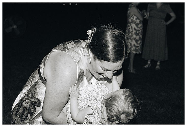 Wedding guests dance the night away in this black and white image of a guest and her baby on the dance floor