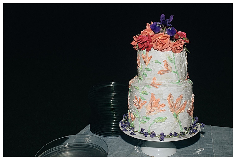 A two tiered wedding cake topped with purple and pink florals