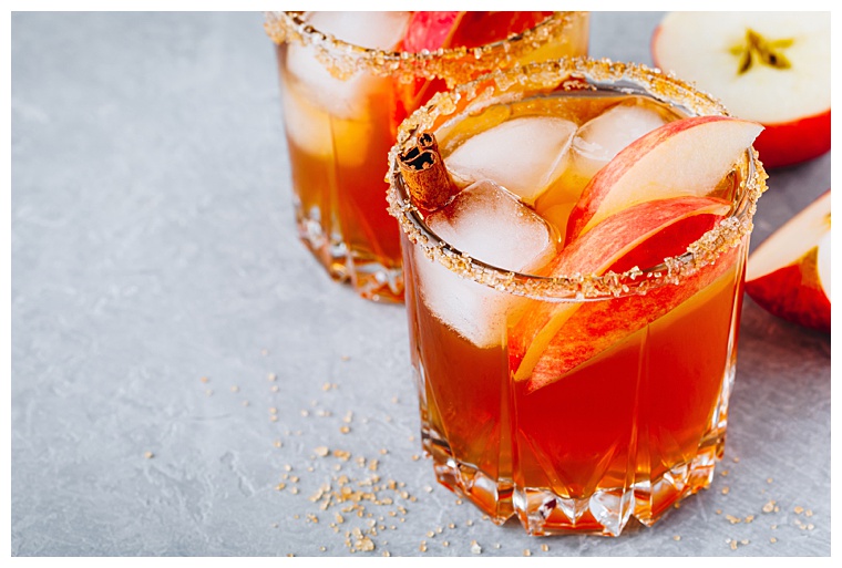 Apple cider margarita with cinnamon and ice for Halloween or Thanksgiving in glass on gray stone background
