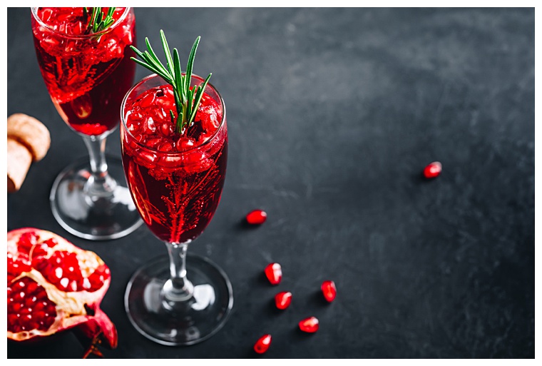 Pomegranate Champagne Cocktail with rosemary on gray concrete stone background, copy space