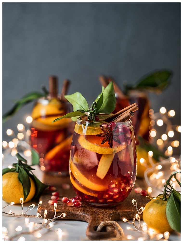 Winter sangria on dark christmas holiday background. Jugful of sangria and glasses with fruit slice, pomegranate and spices. Copy space for text or design. Vertical.