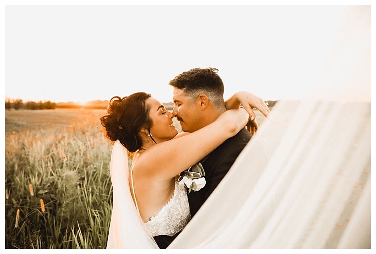 A gorgeous golden hour bridal portrait with the bride's veil sweeping a frame of the image