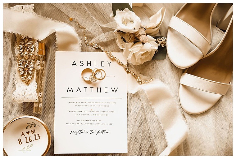 A simple but elegant invitation suite is displayed with wedding day details including the bride's jewelry, shoes, and florals