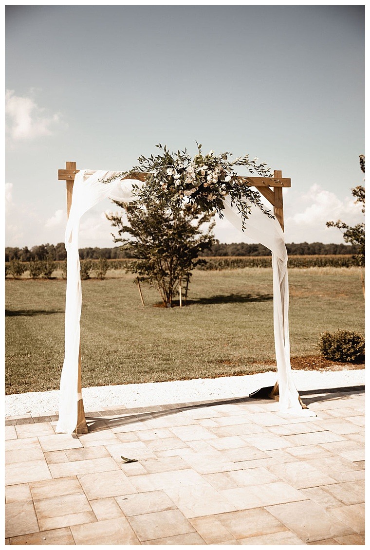 The ceremony site awaits the bride and groom decorated with white drapery and gorgeous green florals by Sherwood Florist