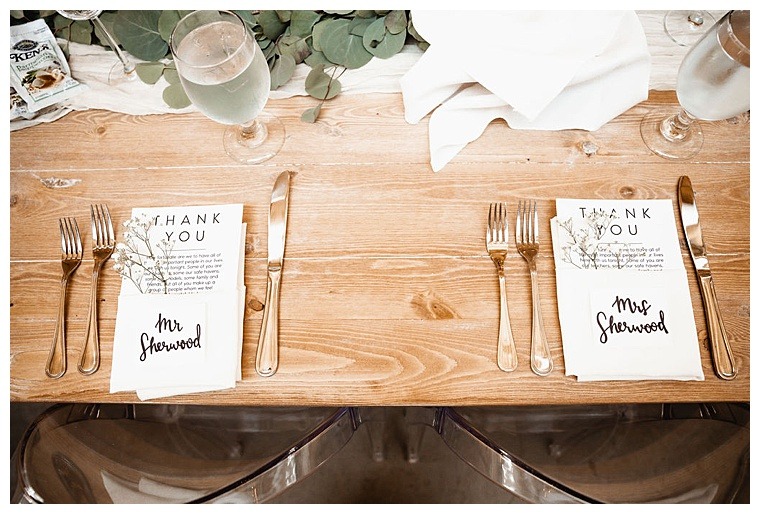 A sweetheart table for the new Mr. and Mrs. is set with greenery and rustic details