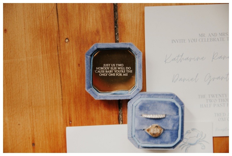 A blue velvet ring box, custom engraved with a message for the newlyweds