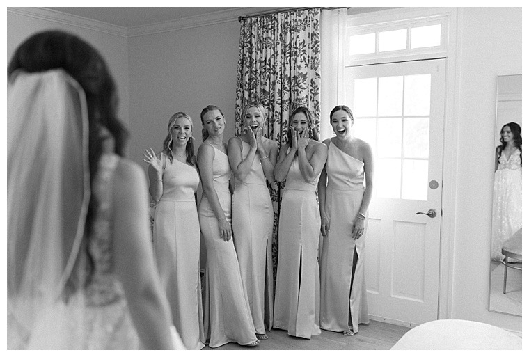 The bridesmaids are all smiles as they get their first glimpse of the bride in her wedding gown