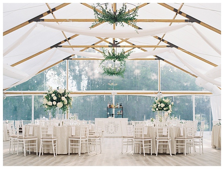 Chandeliers of greenery hang over the dance floor in this white reception space
