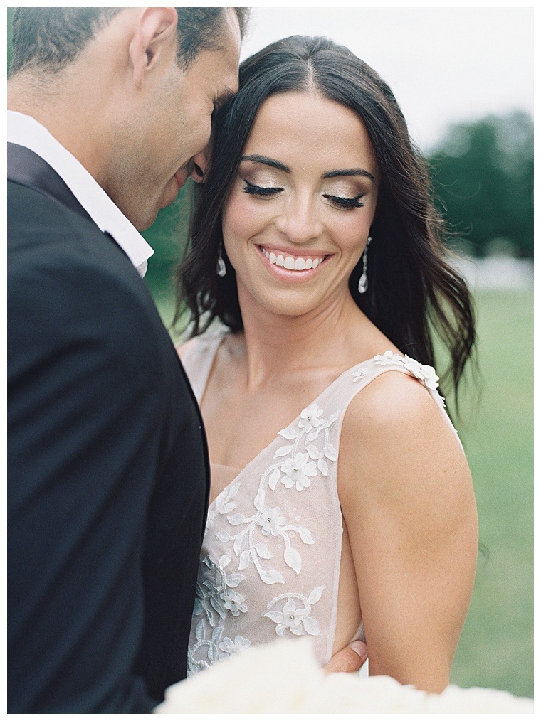 The beautiful bride is all smiles as the groom whispers in her ear before the ceremony