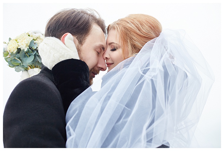Bride and groom hugging and kissing while standing on the street in winter. Wedding, gentle embrace of man and woman. Family, the husband and wife