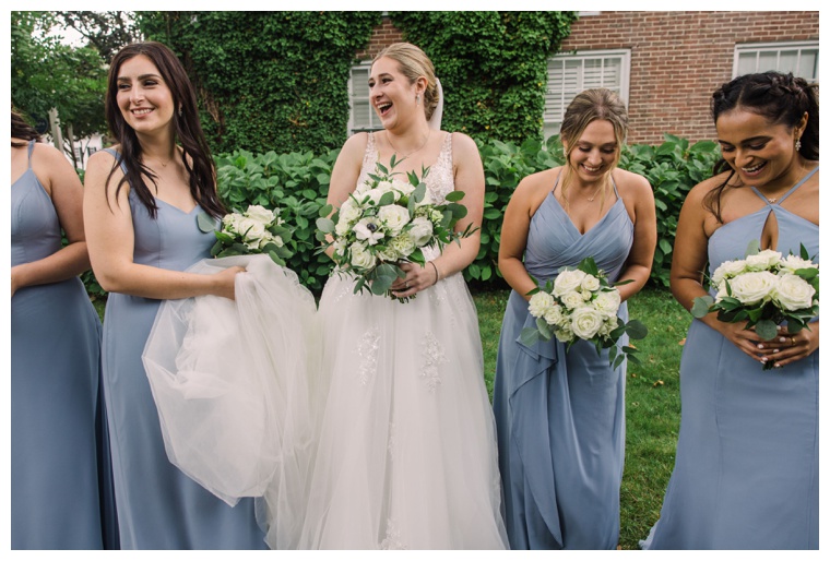 Bridesmaids dressed in a variety of dusty blue styles escort the bride to her wedding ceremony