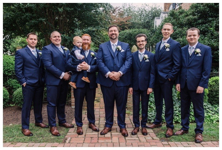Groomsmen pose as a group for a picture in their blue suits