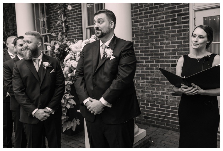 The groom waits to meet his bride at the altar surrounded by friends and stunning florals by Seaberry Farm | Tidewater Wedding Ceremony | Black and White Wedding Photography