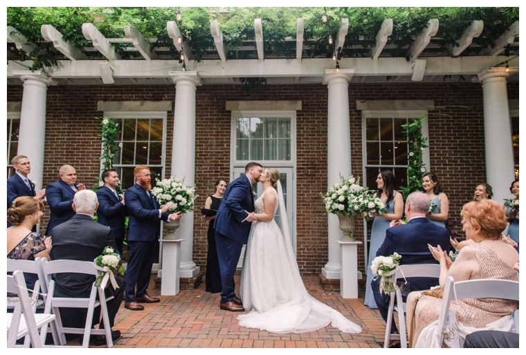 The bride and groom share their first kiss as newlyweds on the patio at the Tidewater Inn