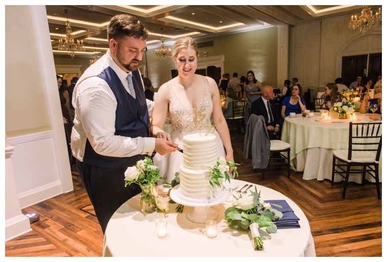 The newlyweds cut the ceremonial first piece of wedding cake during their Tidewater reception 