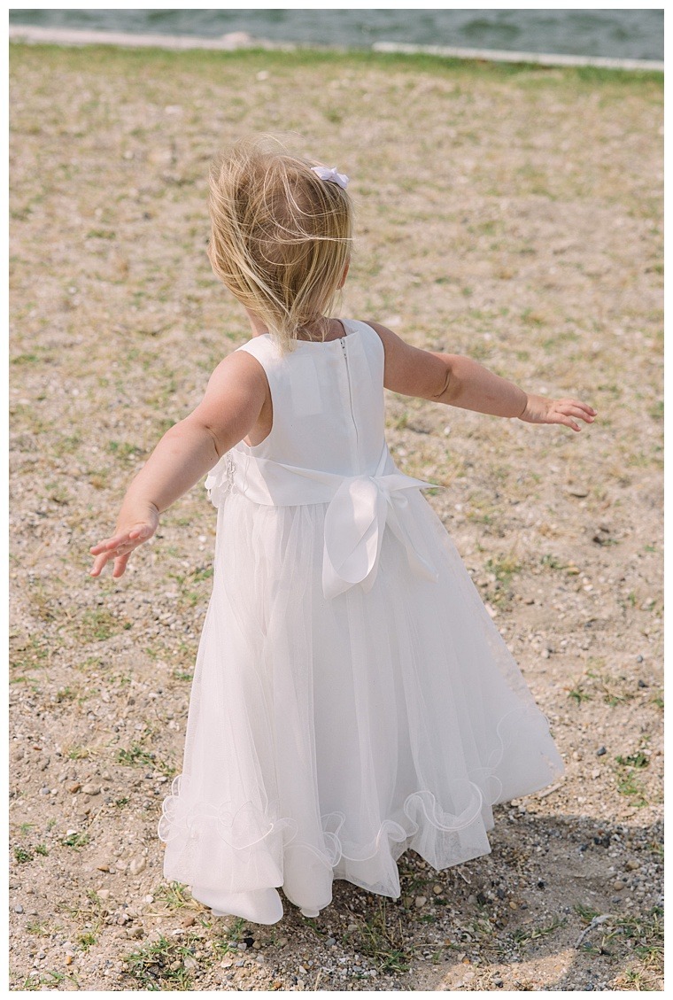 An adorable flower girl dances in the wind on the shores of the Tred Avon River as the wedding day begins