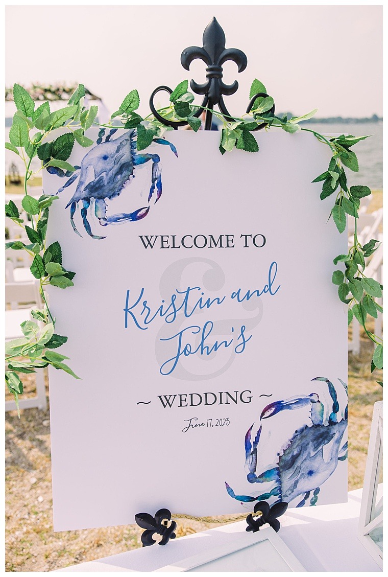 A custom welcome sign with nautical details of Maryland's Infamous Blue Crab welcomes guests to Kristin and Johns wedding day