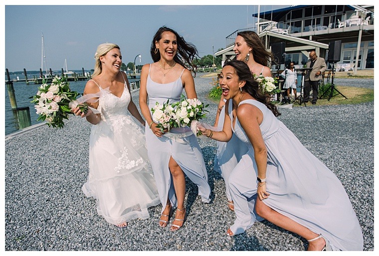 Dressed in cool blues to match the nautical backdrop, the bridesmaids are all smiles celebrating a successful wedding ceremony full of love and laughter