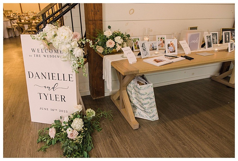 A custom welcome sign for Danielle and Tyler's wedding reception with beautiful florals and a memory table